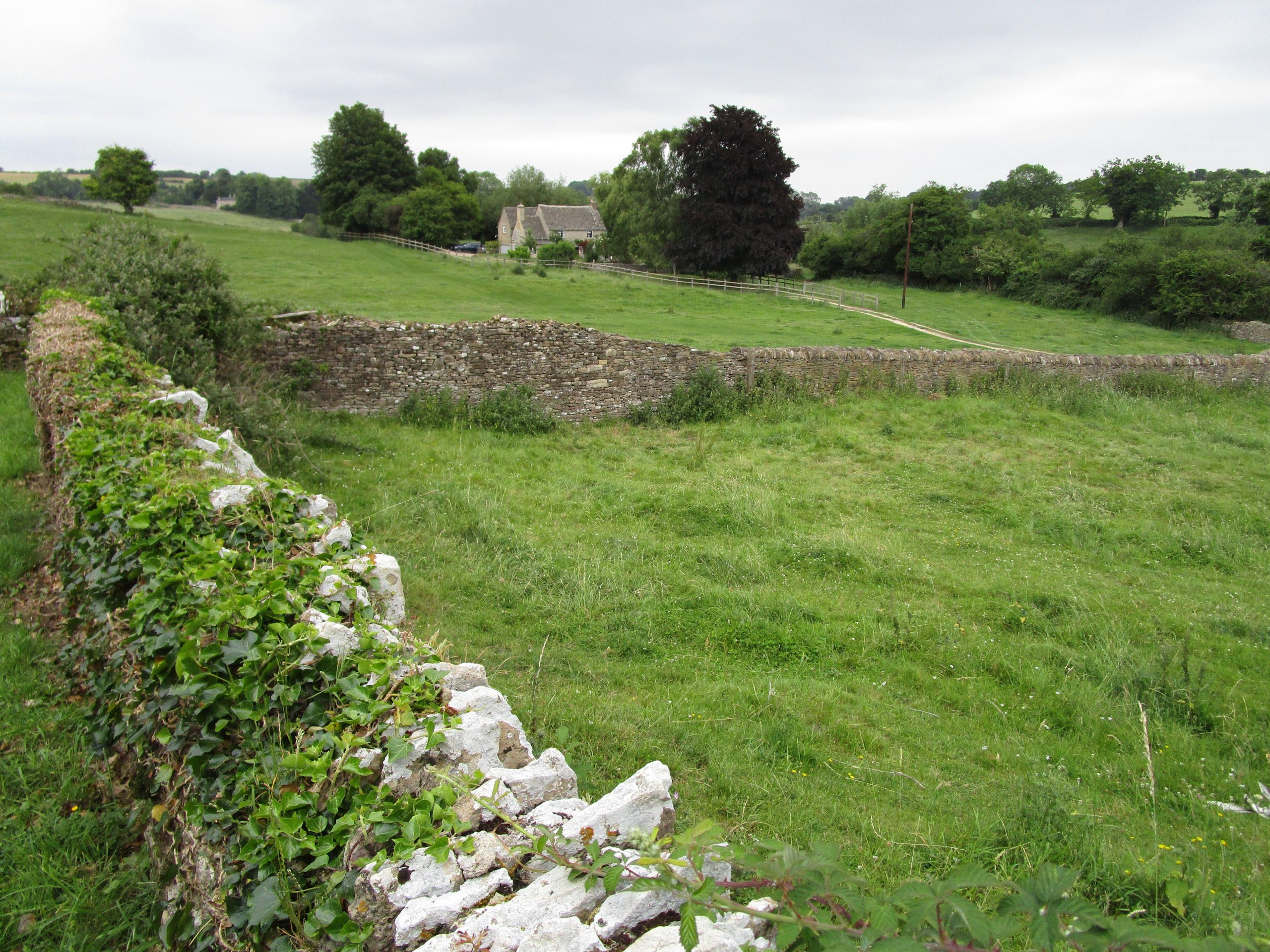 The Making of Us: image of grassy field, stone wall, and small church